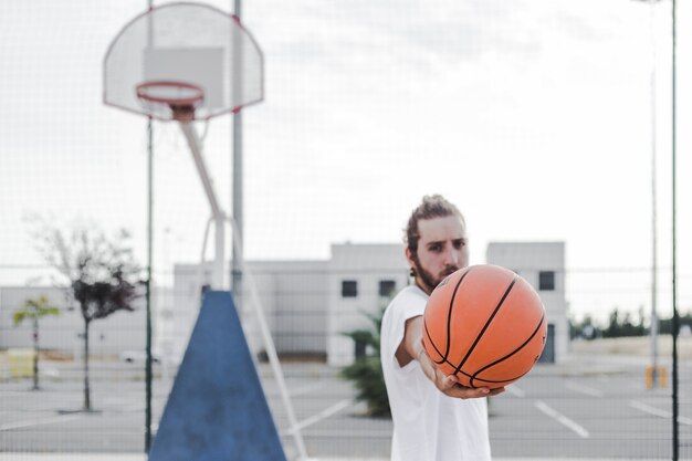 Junger Mann, der im Gericht Basketball zeigt