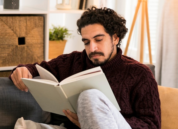 Junger Mann, der im Wohnzimmer liest