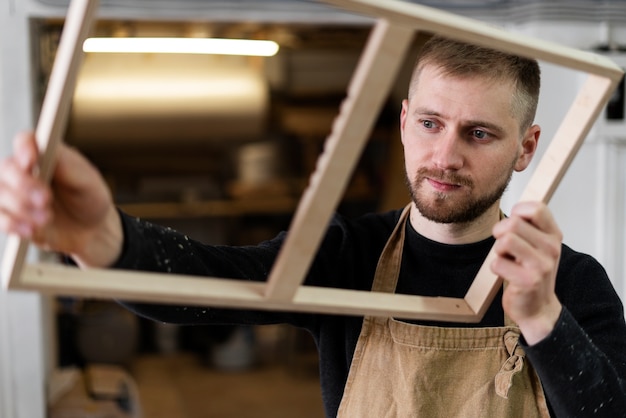 Junger Mann, der in einer Holzstichwerkstatt arbeitet