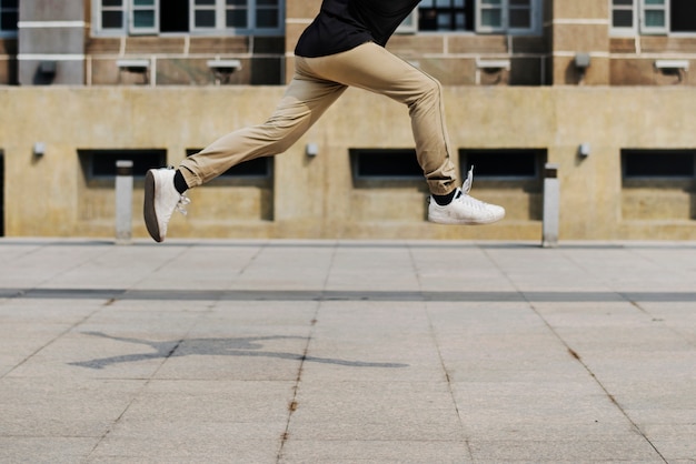 Junger Mann, der in scount des Universitätsgeländegebäudes springt
