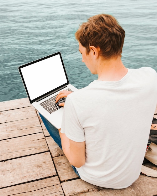 Junger Mann, der Laptop durch das Wasser verwendet