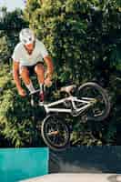 Kostenloses Foto junger mann, der mit bmx fahrrad-totale springt