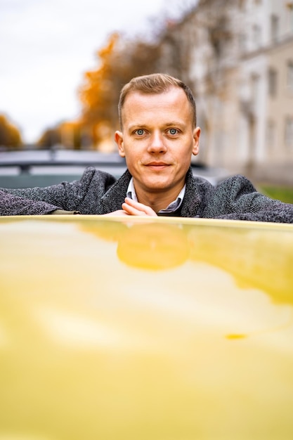 Junger Mann, der mit einem Glas Kaffee in der Herbststadt spazieren geht