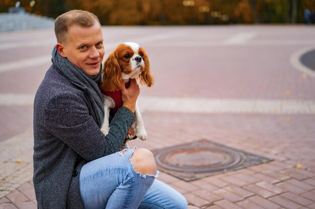 Junger Mann, der mit einem Hund im Herbstpark spaziert