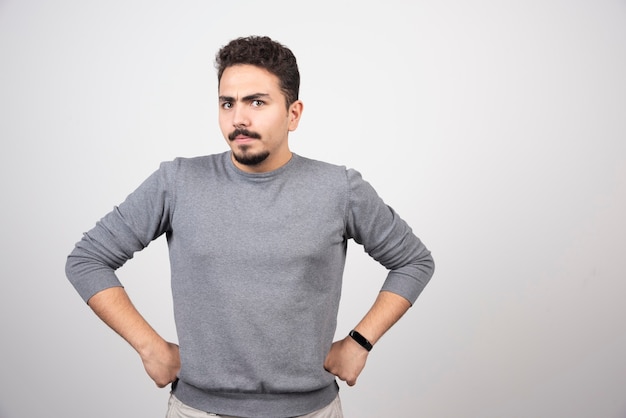 Junger Mann, der mit Händen auf Taille aufwirft und Kamera betrachtet.