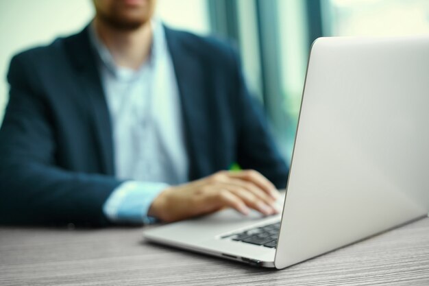 Junger Mann, der mit Laptop, die Hände des Mannes auf Notebook, Geschäftsperson am Arbeitsplatz arbeitet