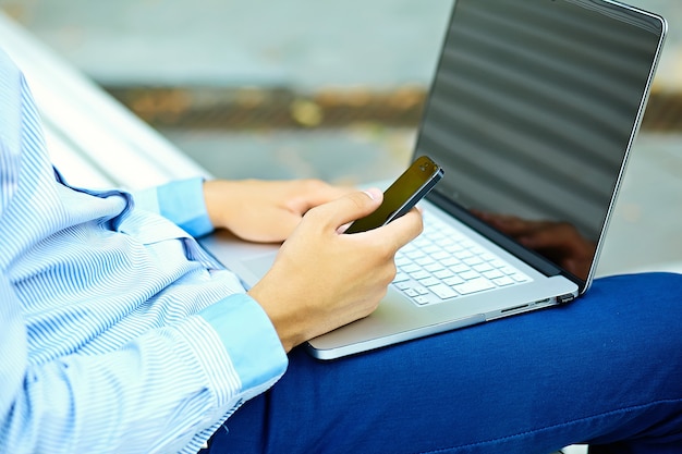 Junger Mann, der mit Laptop, Mannhänden auf Notizbuchcomputer, Geschäftsmann in der Freizeitkleidung in der Straße arbeitet