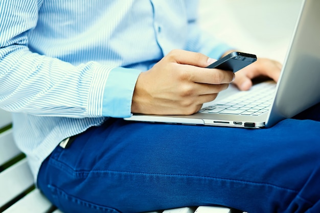 Junger Mann, der mit Laptop, Mannhänden auf Notizbuchcomputer, Geschäftsmann in der Freizeitkleidung in der Straße arbeitet