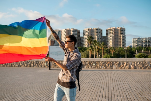 Junger Mann, der mit LGBT-Flagge steht