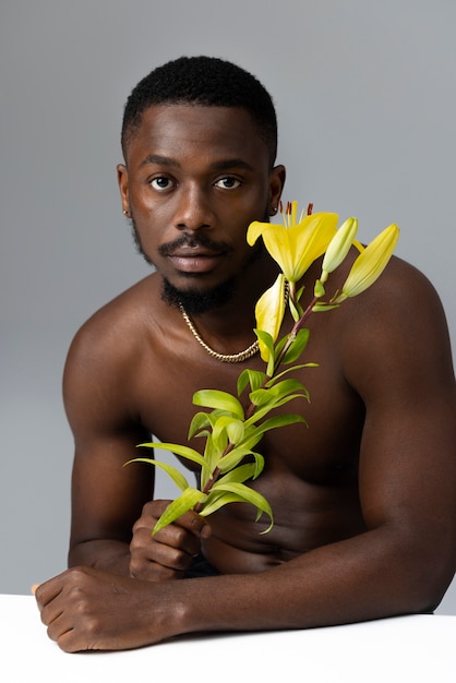 Kostenloses Foto junger mann, der mit mittlerer aufnahme der blume aufwirft