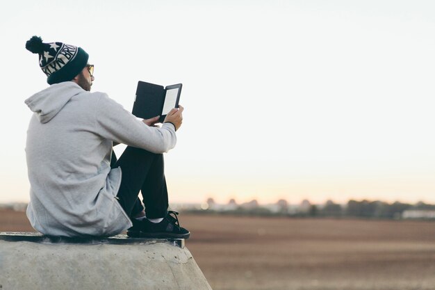 Junger Mann, der mit Tablette auf Natur kühlt