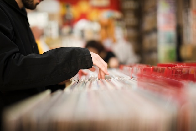 Junger Mann der Nahaufnahme, der nach Vinyls im Speicher sucht