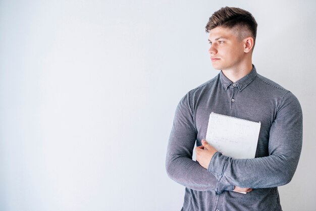 Junger Mann, der Notizbuch im Studio hält