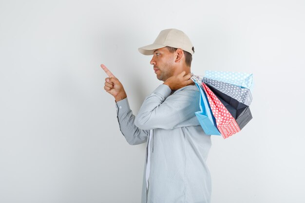 Junger Mann, der Papiertüten mit Finger oben im Hemd hält