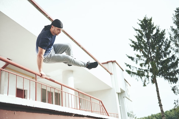 Kostenloses Foto junger mann, der parkour-sprung im städtischen raum im sonnigen frühlingssommertag der stadt tut.