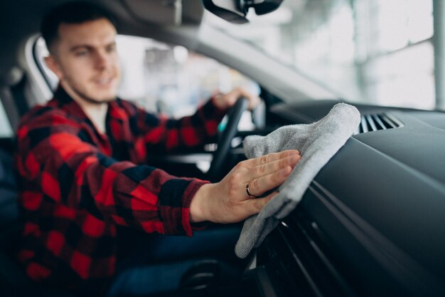 Junger Mann, der sein Auto mit Lappen poliert