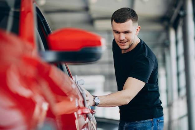 Junger Mann, der sein Auto mit Lappen poliert