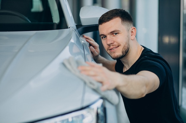 Kostenloses Foto junger mann, der sein auto mit lappen poliert