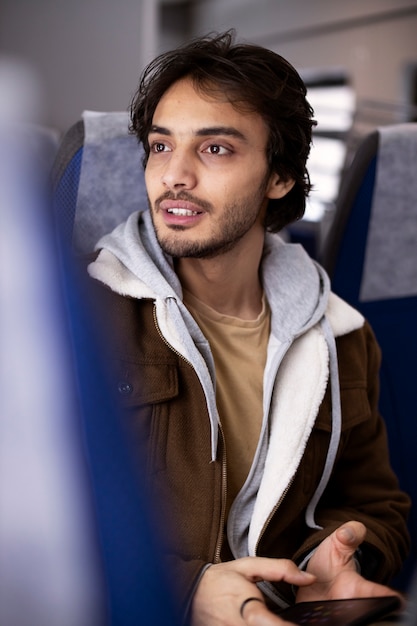 Junger Mann, der sein Smartphone benutzt, während er mit dem Zug fährt