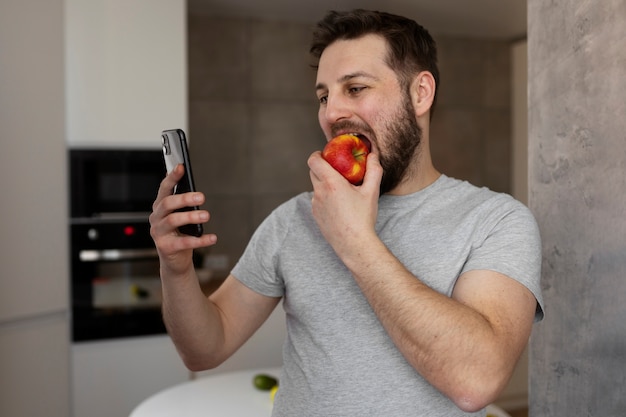 Junger Mann, der sein Smartphone isst und überprüft