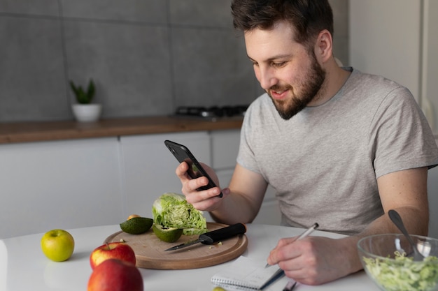 Kostenloses Foto junger mann, der sein smartphone isst und überprüft