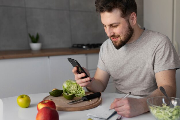 Junger Mann, der sein Smartphone isst und überprüft