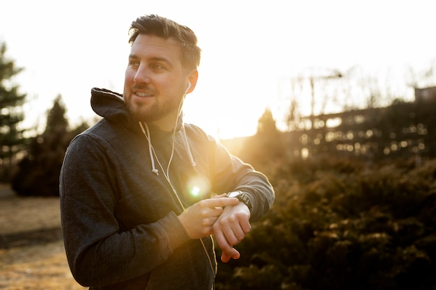 Junger Mann, der sein Smartphone überprüft, während er im Freien trainiert