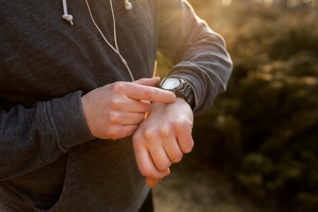 Junger Mann, der sein Smartphone überprüft, während er im Freien trainiert