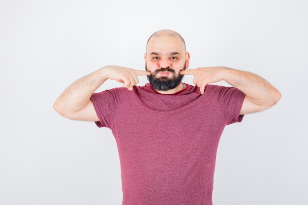 Kostenloses Foto junger mann, der seine aufgeblasenen finger in der vorderansicht des rosa t-shirts zusammendrückt.