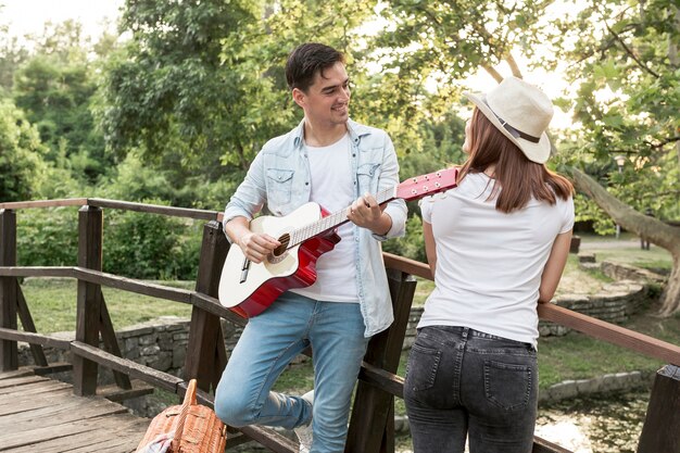 Junger Mann, der seiner Freundin Gitarre spielt