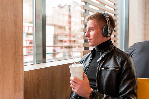 Junger Mann der Seitenansicht, der nach innen Musik auf Kopfhörern hört