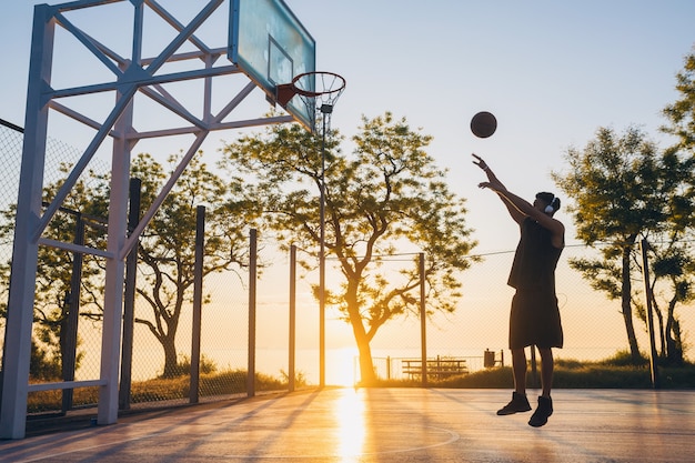 Junger Mann, der Sport macht, Basketball bei Sonnenaufgang spielt