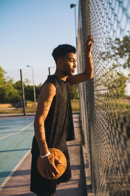 Junger Mann, der Sport macht, Basketball bei Sonnenaufgang spielt