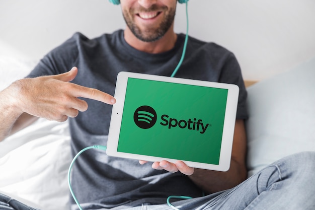 Junger Mann, der Tablette mit spotify APP hält