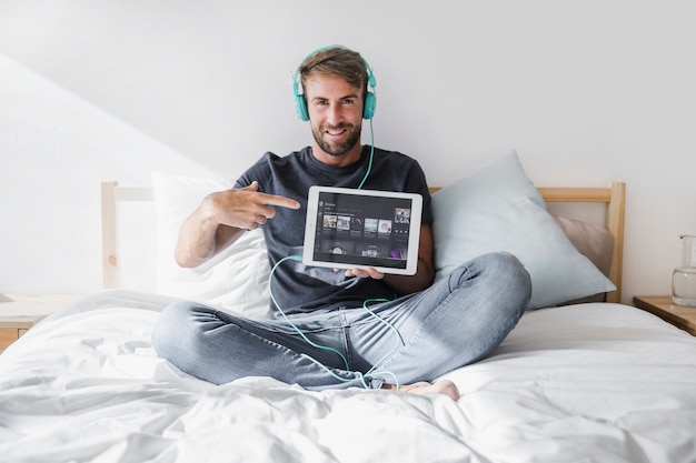 Junger Mann, der Tablette mit spotify APP hält