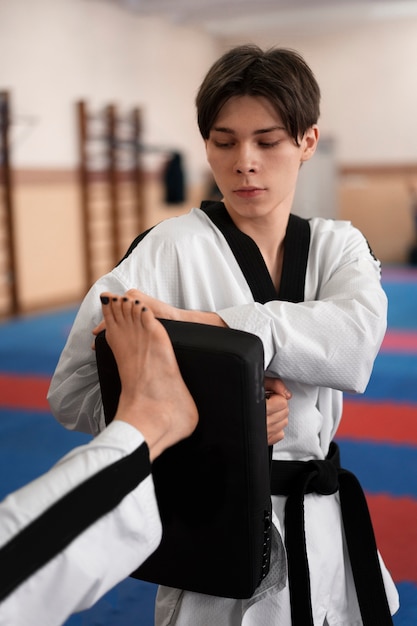 Kostenloses Foto junger mann, der taekwondo in einer turnhalle übt