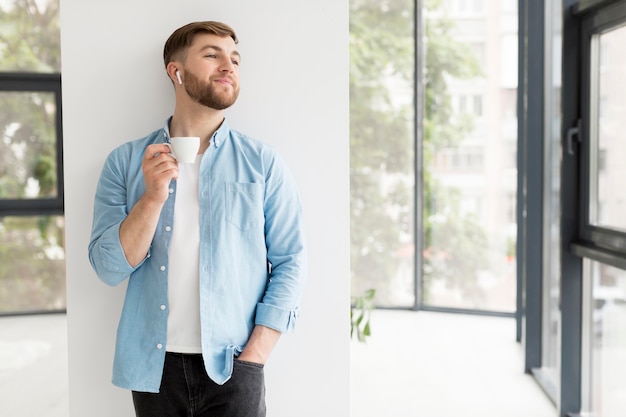 Junger Mann, der Tasse Kaffee genießt