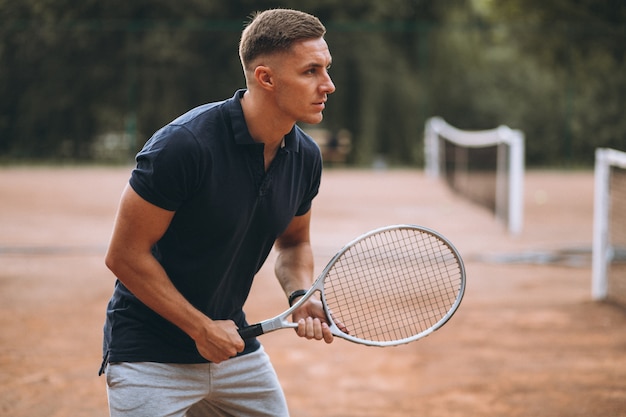 Junger Mann, der Tennis am Gericht spielt