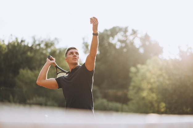 Junger mann, der tennis am gericht spielt