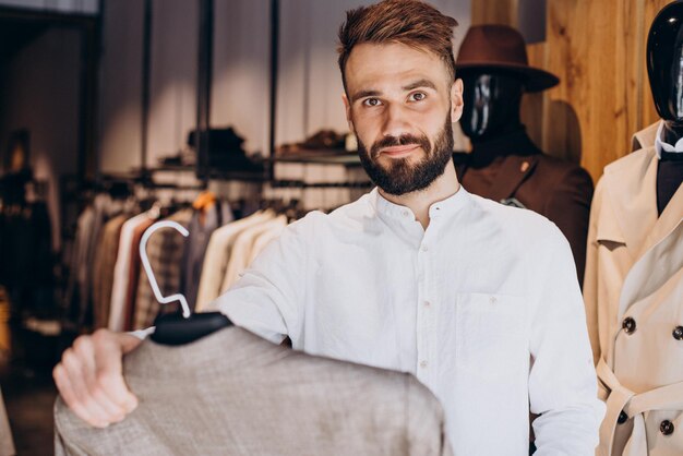 Junger Mann, der Tücher im Herrenbekleidungsgeschäft auswählt