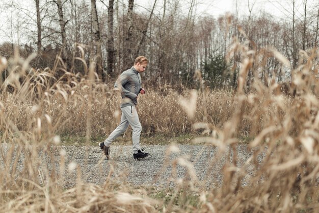 Junger Mann, der über die Pfütze auf Schotterweg springt