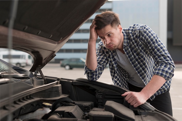 Junger Mann, der versucht, Auto zu reparieren