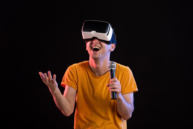 Junger Mann, der virtuelle Realität spielt und auf der dunklen Oberfläche singt