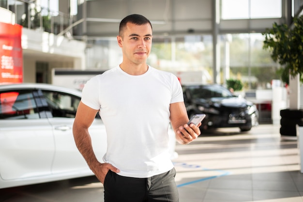 Kostenloses Foto junger mann der vorderansicht an einem autohaus