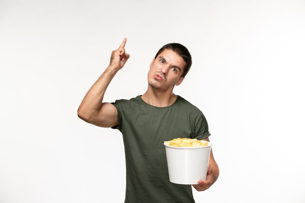 Junger Mann der Vorderansicht im grünen T-Shirt mit Kartoffelspitzen auf dem einsamen Filmkino der weißen Wandperson