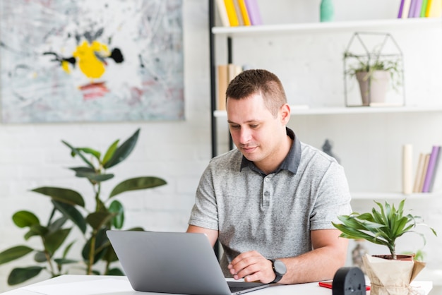 Junger Mann, der zu Hause an Laptop arbeitet