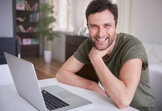 Junger Mann, der zu Hause mit seinem Laptop arbeitet