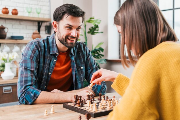 Junger Mann, der zu Hause Schach mit seiner Frau spielt
