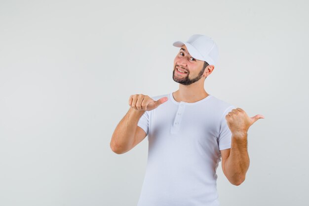 Junger Mann, der zurück in T-Shirt zeigt und glücklich schaut. Vorderansicht.