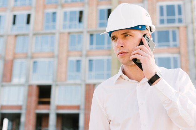 Junger Mann des mittleren Schusses mit Sturzhelm sprechend am Telefon